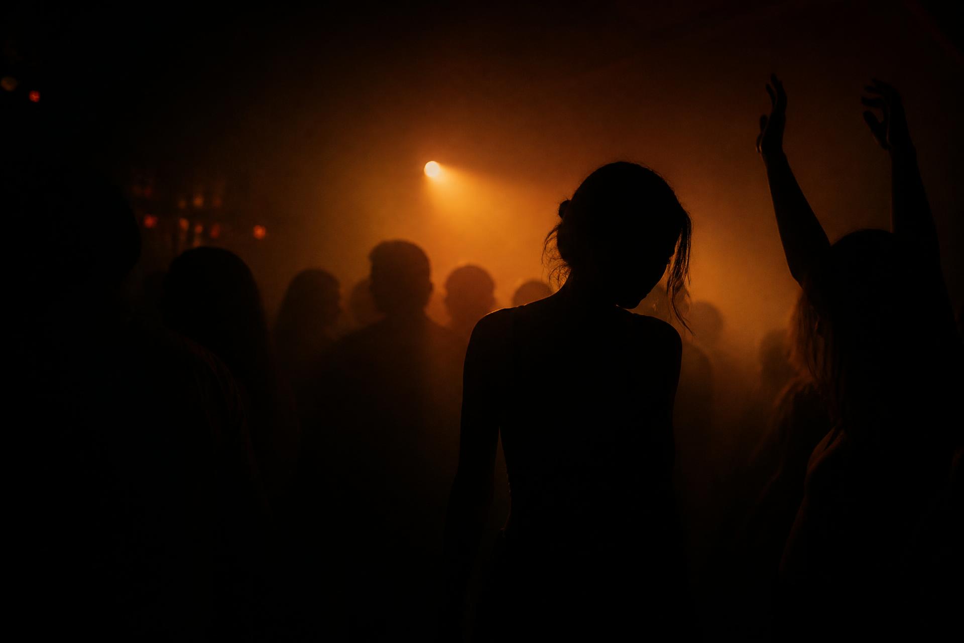 Silhouettes in haze under a single amber beam